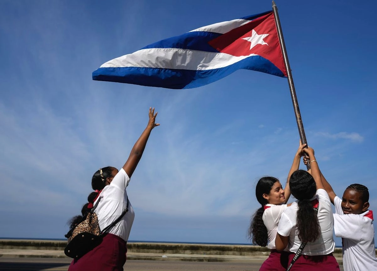Estudiantes cubanos, en una imagen de 2024, ondean la bandera durante los festejos de la entrada triunfal de Fidel Castro y el Movimiento 26 de Julio a La Habana en 1959. 