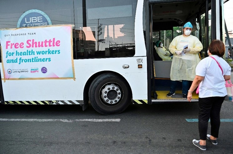 Un trabajador de salud (der.) con un asistente de un autobús de enlace durante la cuarentena impuesta por el gobierno filipino como medida preventiva contra el nuevo coronavirus en, Manila. Foto Afp