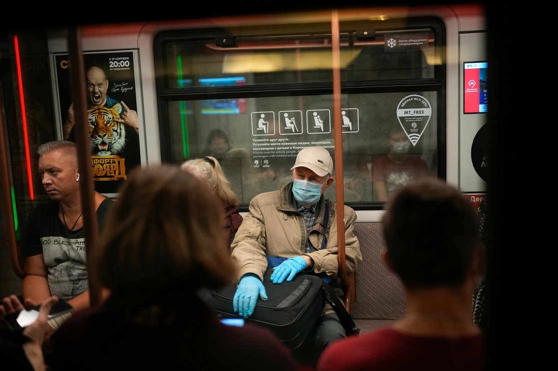 Un pasajero con guantes y crubrebocas y otro sin protección alguna, en el Metro de Moscú, el 12 de septiembre de 2021. Foto Ap