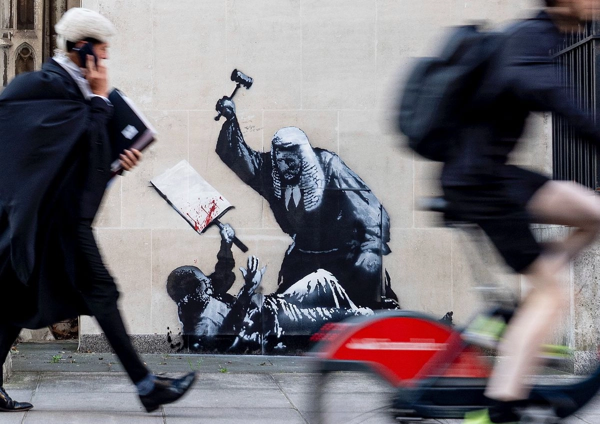 La nueva obra de arte del artista Banksy retrata a un juez golpeando a un manifestante con un mazo en los Tribunales Reales de Justicia de Londres.