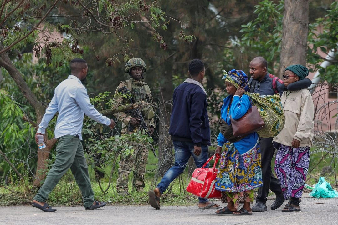 Un miembro del grupo armado M23 se posiciona tras una alambrada mientras civiles que huyen de los enfrentamientos en curso en el este de la República Democrática del Congo cruzan la frontera con Ruanda por el puesto fronterizo de La Corniche en Gisenyi el 29 de enero de 2025. Foto