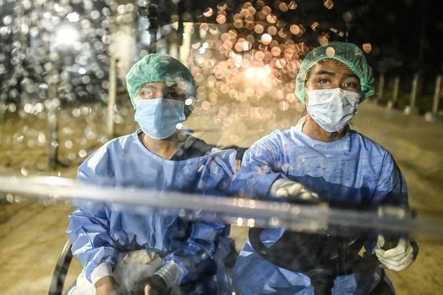 Voluntarios con trajes protectores contra el coronavirus, se trasladan en un centro de cofinamiento en Yangón, Birmania. Foto Afp 