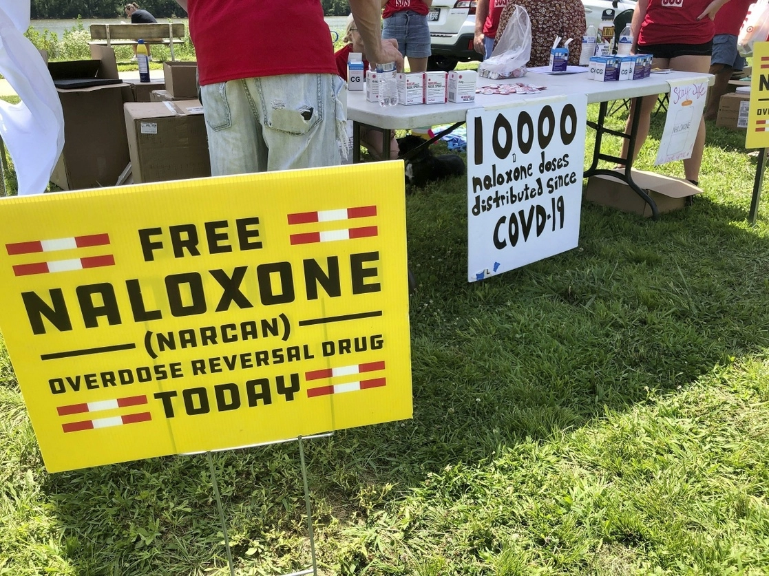 Letrero en una carpa durante un evento de salud, donde los voluntarios dieron dosis gratuitas de naloxona, una droga que revierte los efectos de una sobredosis de opioides al ayudar a la persona a respirar de nuevo en Charleston, Virginia Occidental, el 26 de junio de 2021. Foto Ap 