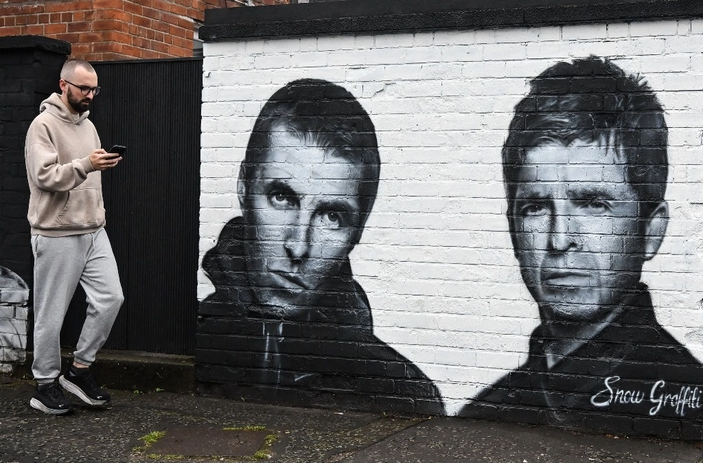 Una persona camina junto a un mural creado por el artista Scott Wilcock, también conocido como ‘Snow Graffiti’, que representa a Liam Gallagher (izq.) y Noel Gallagher (der), miembros de la banda de rock británica Oasis, y que fue pintado afuera del pub Whitefield, cerca de Heaton Park, en Manchester, al norte. Inglaterra, el 2 de septiembre de 2024. Foto Afp