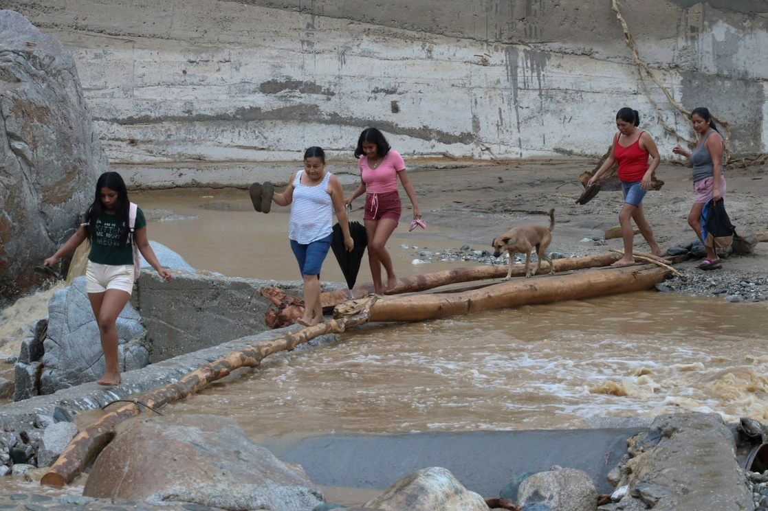 Personas cruzan un puente luego del paso del huracán Ágatha en Huatulco, Oaxaca. Foto Afp