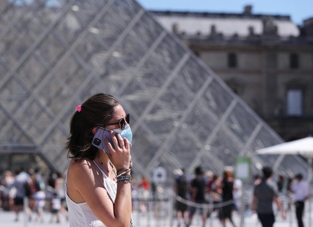 Una mujer con cubrebocas frente a la Pirámide del Museo del Louvre, en París. Foto Xinhua 