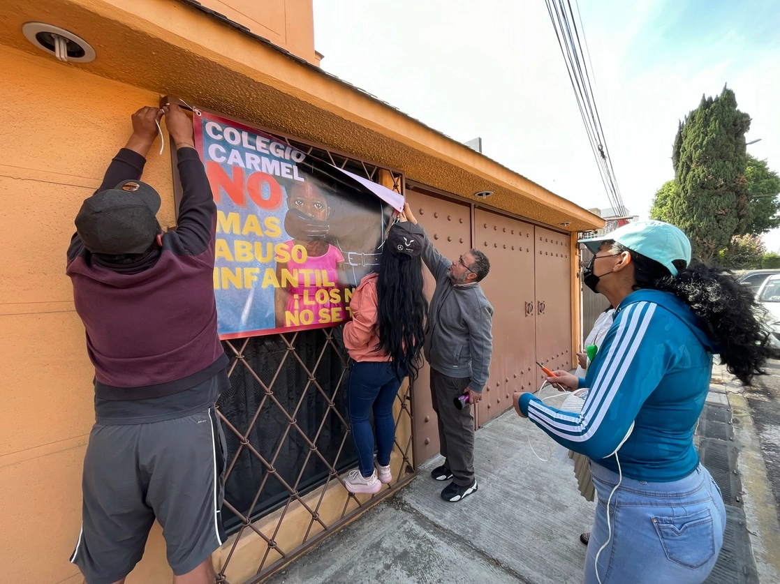 Familiares de una víctima de abuso en el Colegio Carmel, en Coyoacán, al denunciar las agresiones en una manta. Autoridades de la CDMX colocaron ayer sellos de suspensión de actividades en el plantel. Foto Alfredo Domínguez
