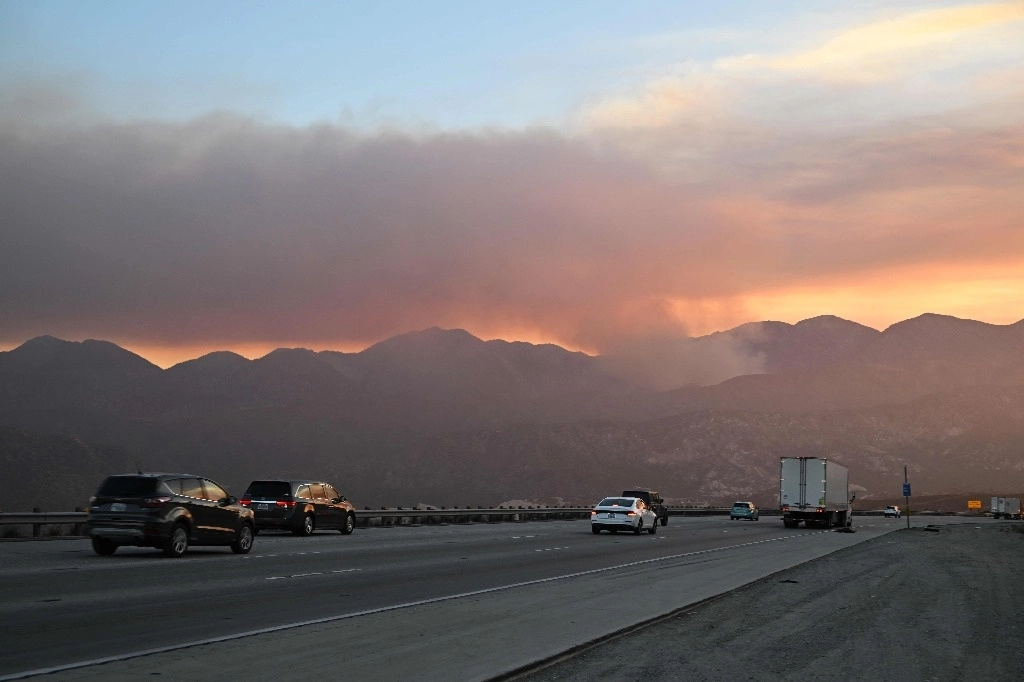Esta imagen tomada el 7 de julio de 2024 cerca de Oak Hills, California, muestra el humo que se eleva a lo lejos más allá de la autopista interestatal 15 mientras el incendio Vista arde en el Bosque Nacional de San Bernardino. Foto Afp