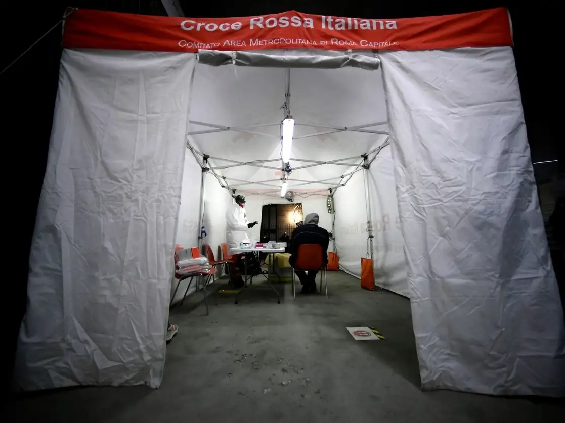 Un indigente espera a que se le aplique la prueba del coronavirus en una tienda de campaña de la Cruz Roja Italiana y Caritas en Roma. Foto Afp 
