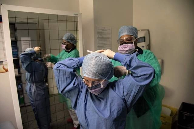 Una enfermera ayuda a una compañera a colocarse el traje protector y una máscara antes de entrar a una zona con enfermos de coronavirus, en el hospital Maria Pia de Turín, Italia. Foto Afp 