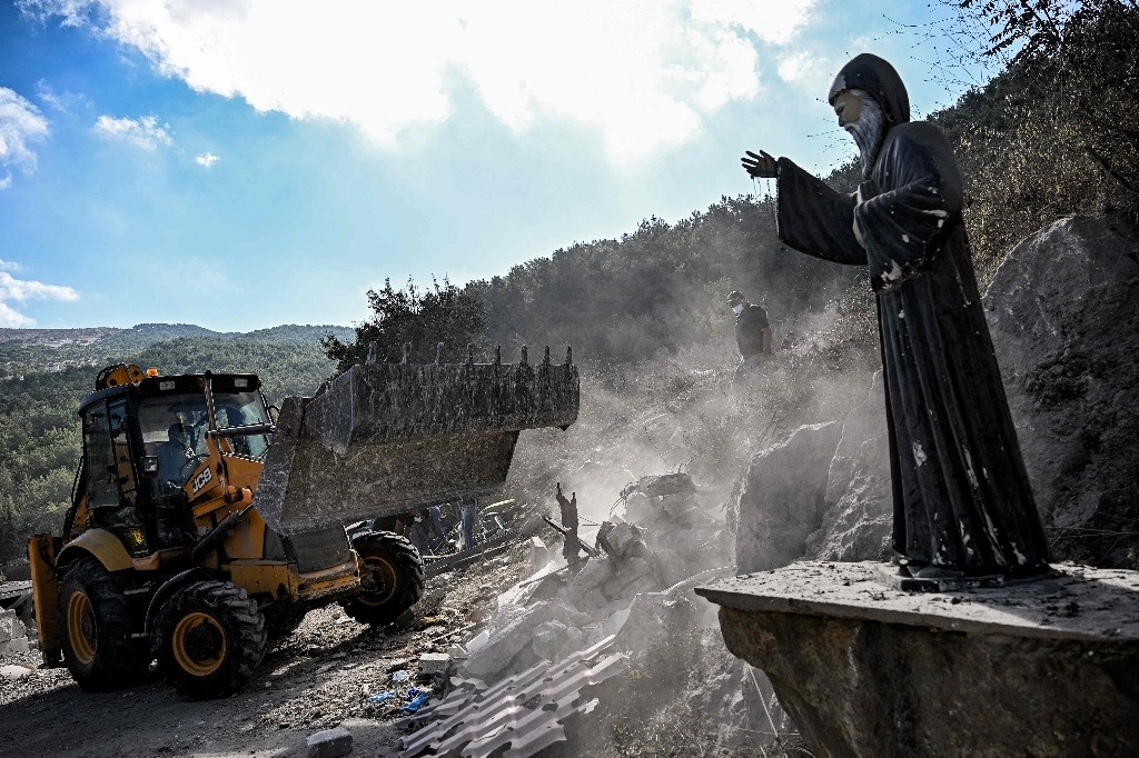 Una estatua de San Charbel quedó en medio de los escombros que dejó un ataque aéreo israelí en la localidad de Aito, en el norte de Líbano. La Cruz Roja de ese país informó que al menos 18 personas murieron en el bombardeo del lunes. Foto Afp 