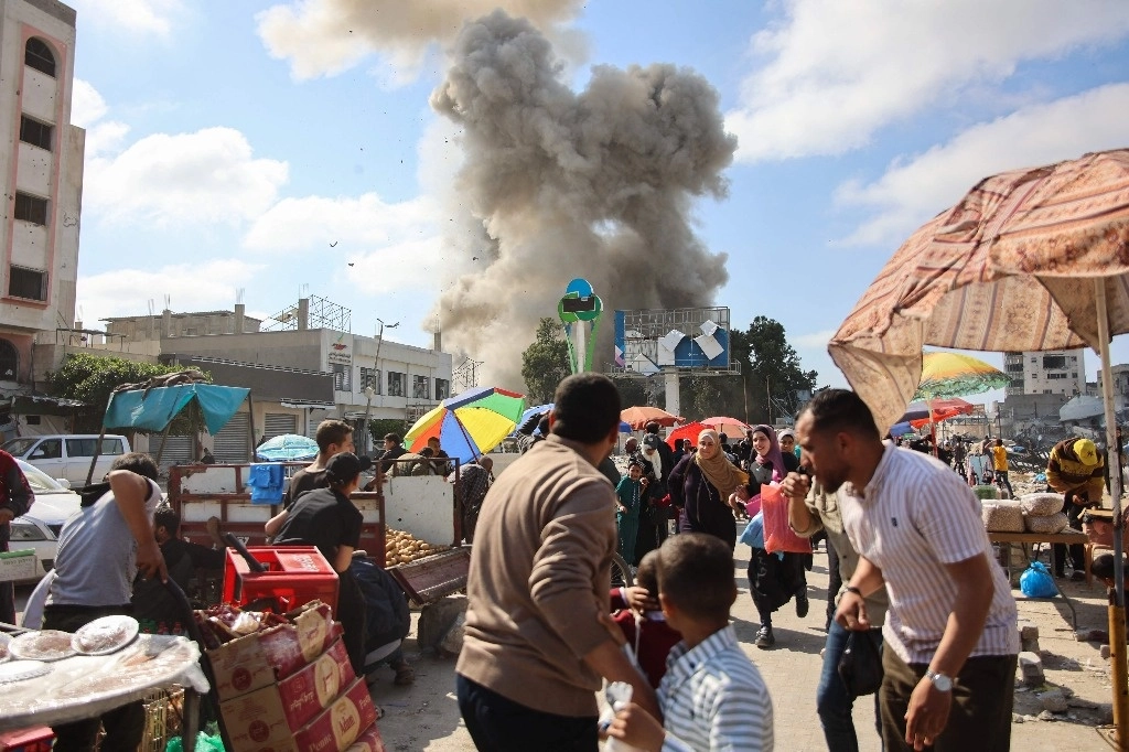 Palestinos observan una gran columna de humo durante un bombardeo israelí en el área del mercado Firas, en Gaza, el 11 de abril de 2024. Foto Afp 