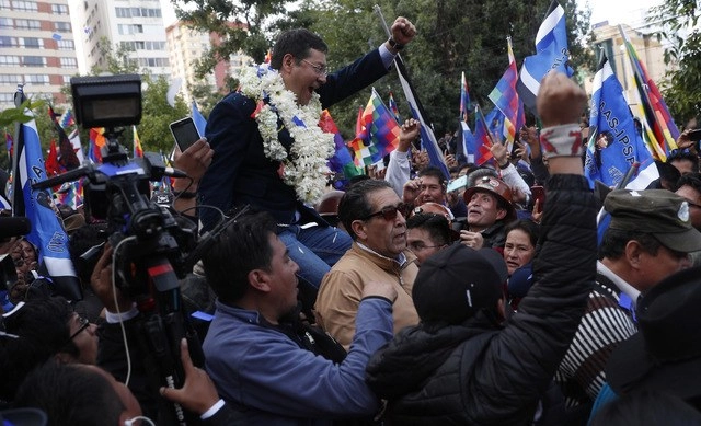 El candidato presidencial del MAS, Luis Arce, es cargado por sus simpatizantes, en imagen de antier en La Paz, Bolivia. Foto Ap 
