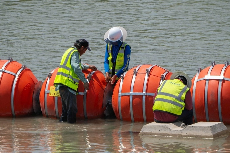 Trabajadores del gobierno de Texas dan mantenimiento a las boyas colocadas en julio pasado en más de 300 metros del río Bravo, cerca de la ciudad de Eagle Pass, para impedir el ingreso de indocumentados desde México. Foto Afp / Archivo