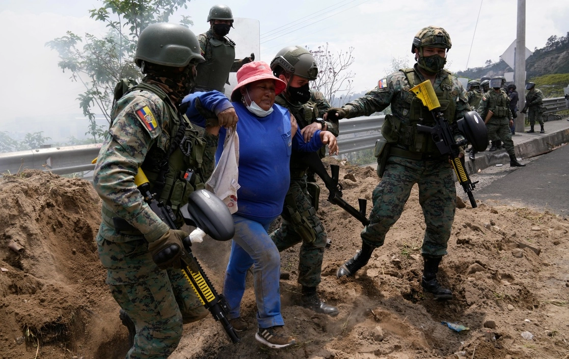 Soldados auxilian a mujer alcanzada por gases lacrimógenos durante las protestas en Ecuador. Foto Ap
