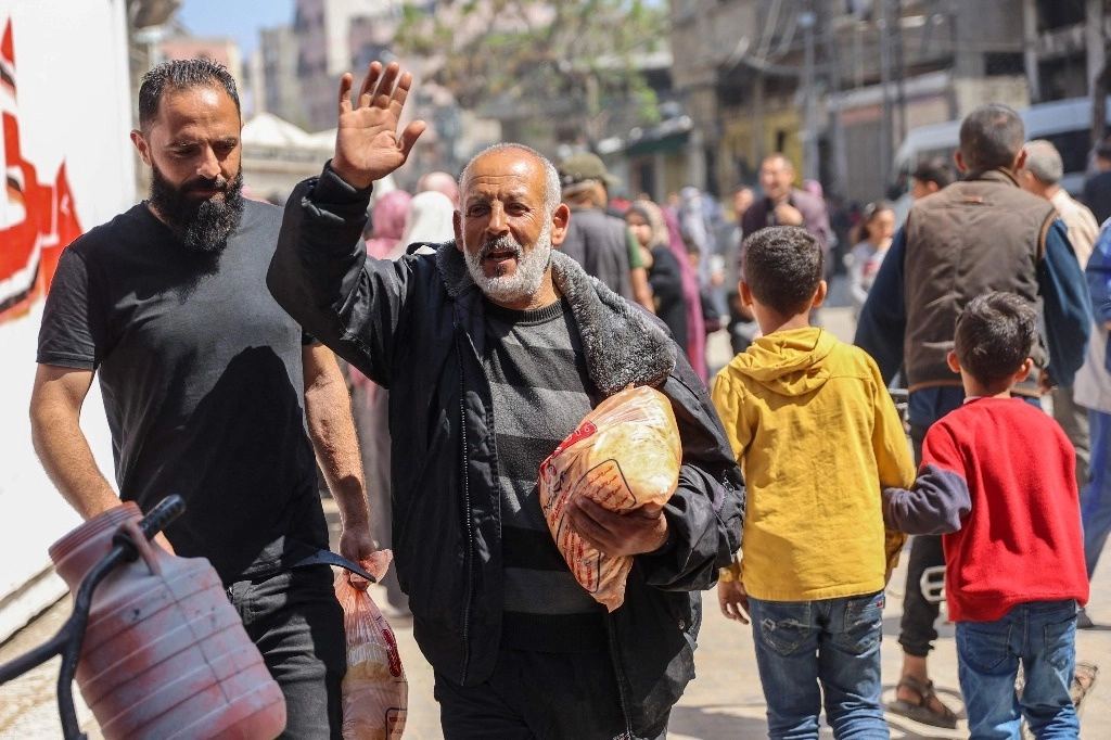 Hombres palestinos tras compran pan subsidiado en una panadería en la franja de Gaza. Foto Afp