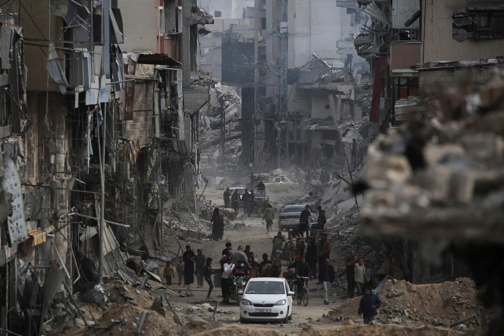 Los palestinos pasan junto a edificios dañados en Khan Yunis el 8 de abril de 2024 después de que Israel retirara sus fuerzas terrestres del sur de la Franja de Gaza, seis meses después de la devastadora guerra provocada por los ataques del 7 de octubre. Foto Afp 