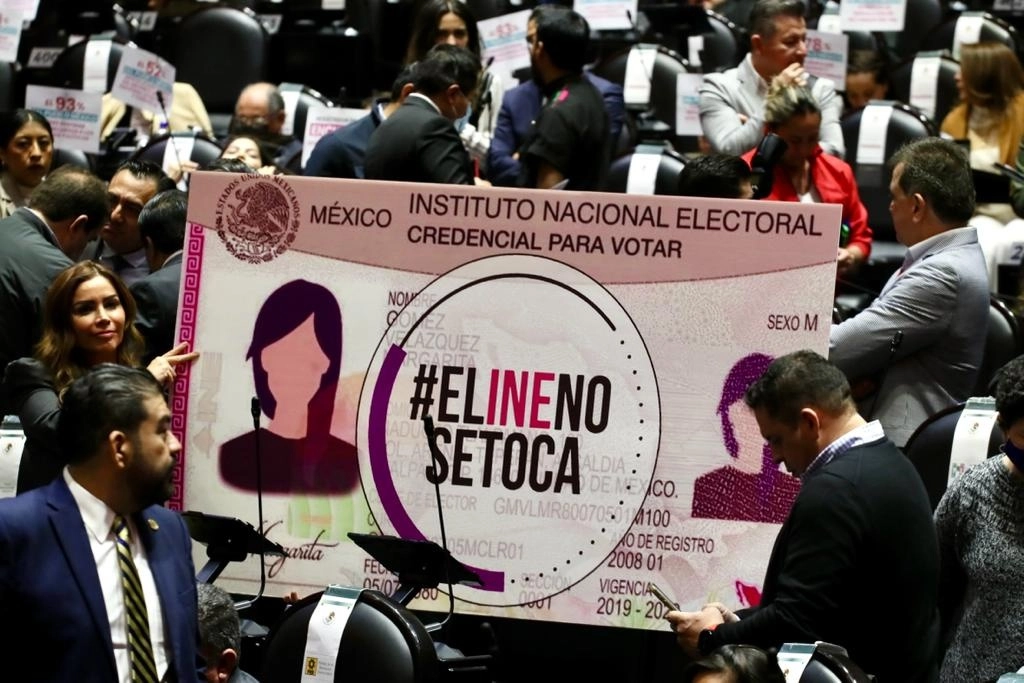 Diputados de oposición sostienen la imagen a gran escala de una credencial para votar emitida por el INE durante la sesión en la Cámara de Diputados, ayer 6 de diciembre. Foto Roberto García Ortiz 