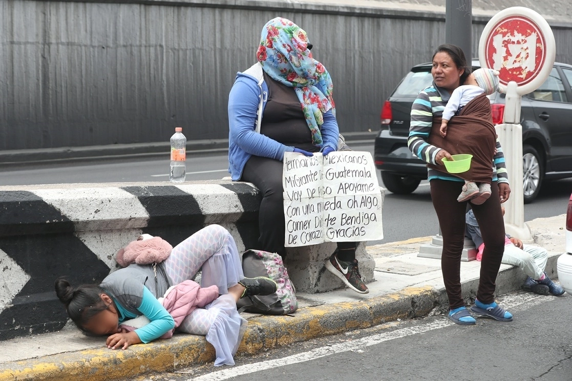 Mujeres migrantes con niños piden ayuda en una entrada hacia carriles centrales de Viaducto, en la Ciudad de México. Foto José Antonio López / Archivo