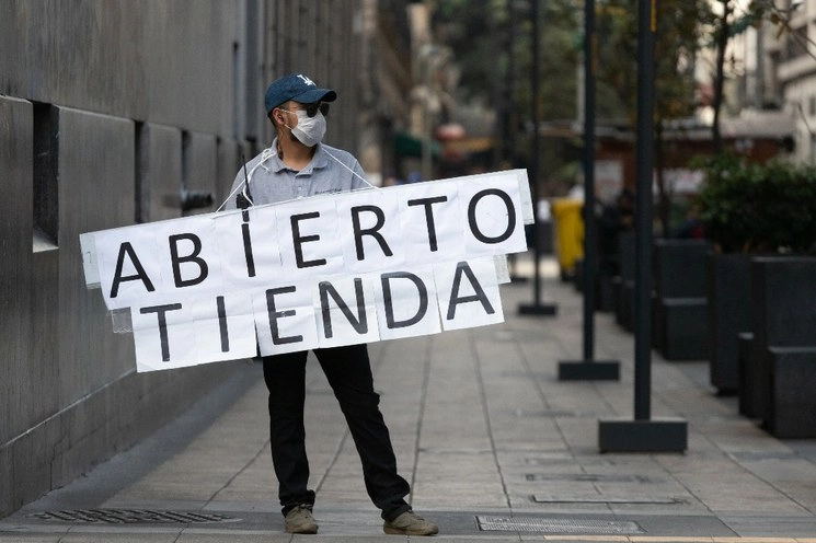 Una persona sujeta un letrero con la leyenda "tienda abierta" en calles del Centro Histórico de la CDMX. Foto Pablo Ramos