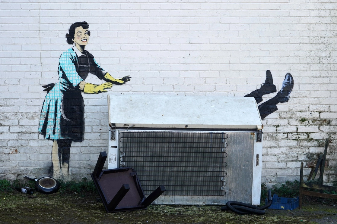 Una obra del Banksy en la que muestra a una mujer, con un ojo morado y un diente roto, mientras empuja a un hombre a un congelador, apareció en el costado de una casa en Margate, Inglaterra, en el día de San Valentín, 14 de febrero de 2023. Foto Afp