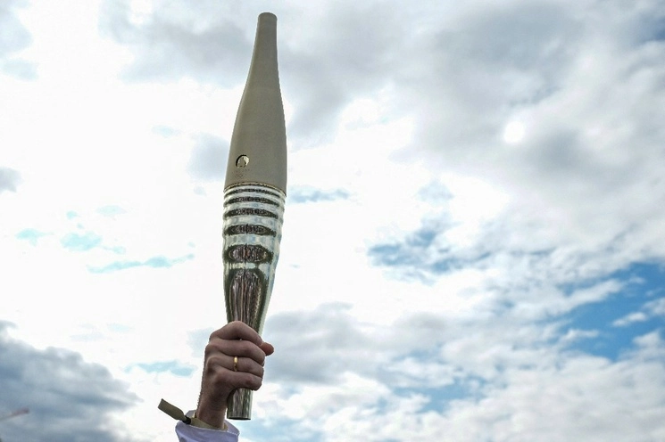 Un participante sostiene la antorcha olímpica durante su presentación en los muelles del río Sena, en París, el 25 de julio de 2023. Foto Afp
