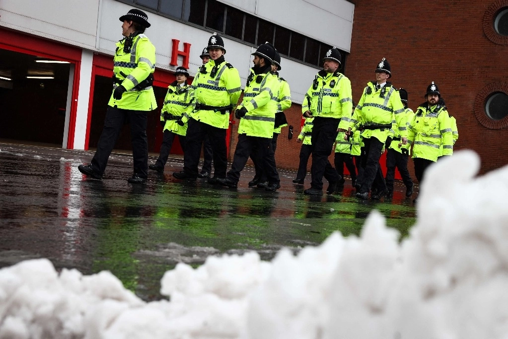 Los agentes de policía patrullan junto a un montón de nieve en las afueras de Anfield en Liverpool, noroeste de Inglaterra, el 5 de enero de 2025, antes del partido de fútbol de la Premier League inglesa entre Liverpool y Manchester United. Las fuertes nevadas en algunas partes de Inglaterra provocaron interrupciones para los viajeros aéreos con pistas cerradas en los aeropuertos de Bristol y Liverpool el 5 de enero de 2025. Foto Afp