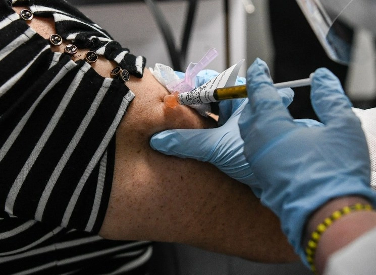 Sandra Rodriguez, de 63 años, recibe una prueba vacunal de parte de Yaquelin De La Cruz, en el Centro de Investigaciones de Estados Unidos, en  Hollywood, Florida, en imagen captada el 13 de agosto de 2020. Foto Afp