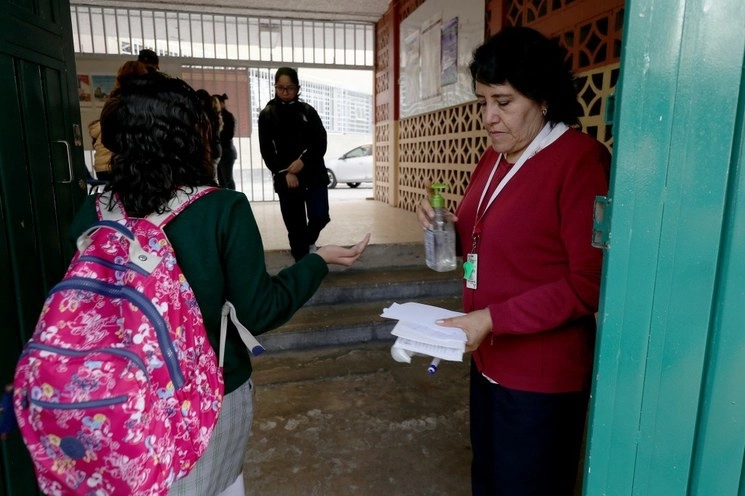 Profesora aplica gel antibacterial a alumnos en la entrada de una escuela en la alcaldía Cuauhtémoc, Ciudad de México. Foto María Luisa Severiano / Archivo