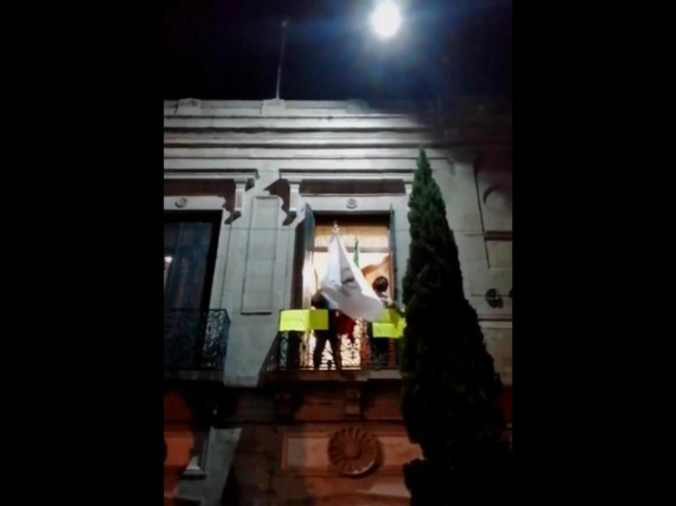 Dos de las personas que demandan ser atendidas por la CNDH ondearon banderas del organismo y de México al recibir el apoyo de organizaciones feministas. Imagen tomada de un video de Colectiva Independiente Revueltas.