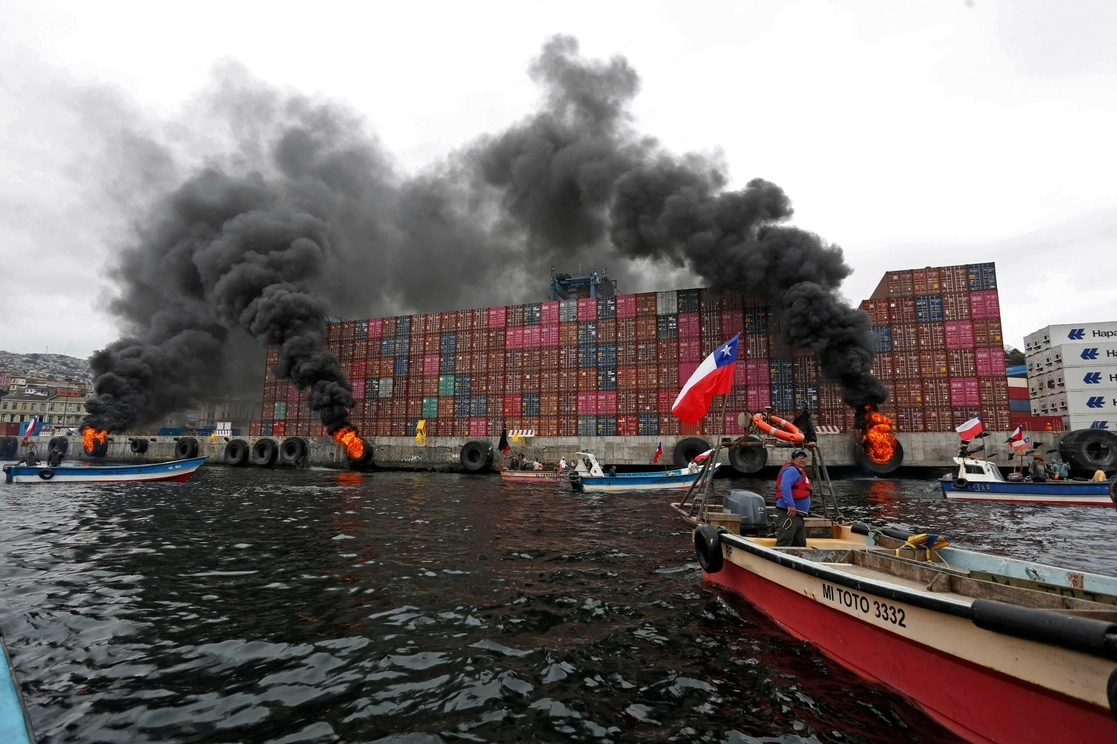 Patrulleros de la marina chilena usaron chorros de agua para apagar el fuego en los muelles y para hacer retroceder a los manifestantes a bordo de lanchas en Valparaíso. Foto Afp