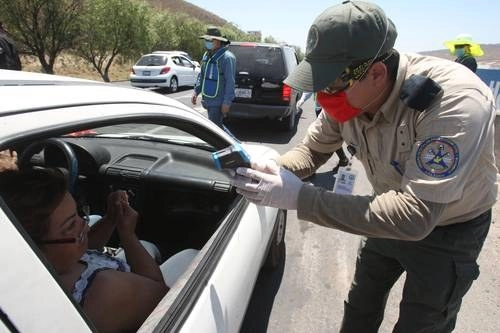 Un elemento de Protección Civil de Jalisco toma la temperatura a una señora en un retén sanitario. Foto Arturo Campos Cedillo

