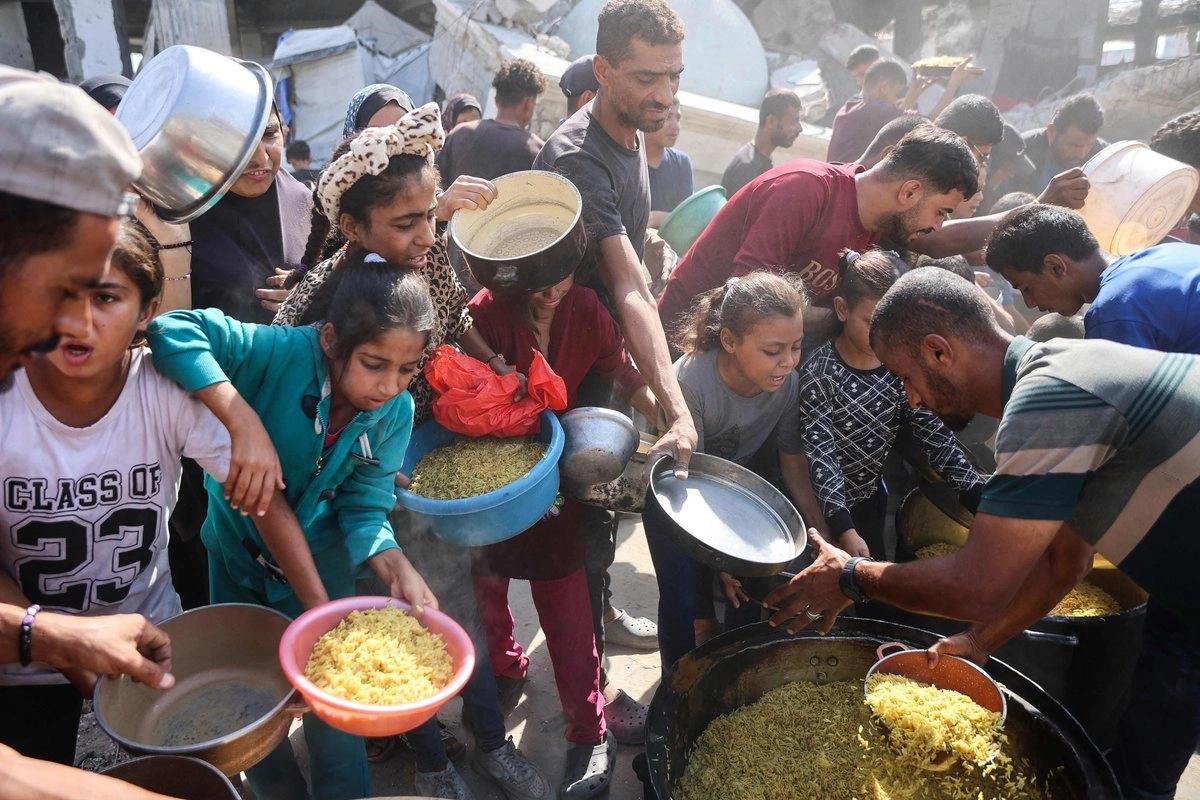 Palestinos desplazados se aglomeran para conseguir comida y agua en la ciudad de Gaza.