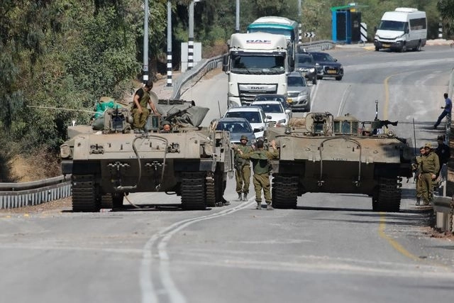Soldados israelíes en vehículos blindados conducen por una calle cerca de la frontera de Líbano. Foto Afp