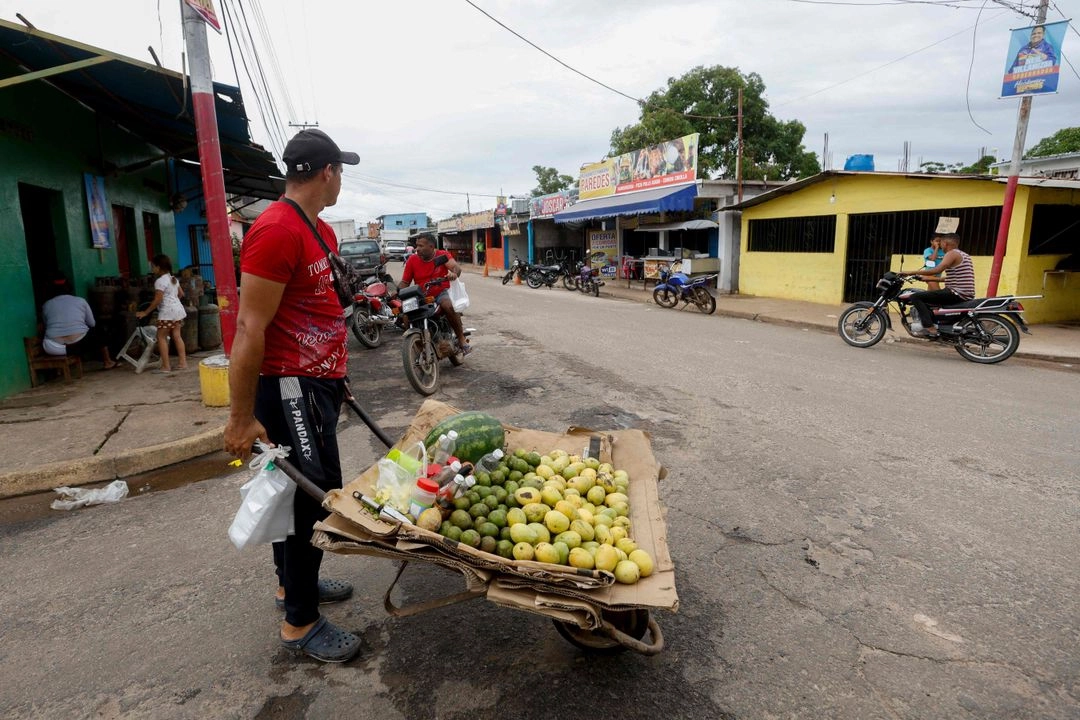 Un hombre lleva una canasta de mangos mientras cruza una calle en la ciudad minera de El Dorado, estado Bolívar, Venezuela, el 24 de mayo de 2025.