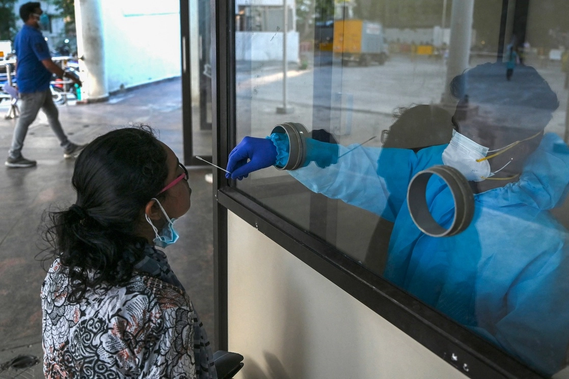 En Chennai, India, personal de salud toma las muestras para la detección del virus a través de una pantalla de cristal, el 6 de enero de 2022. Foto Afp