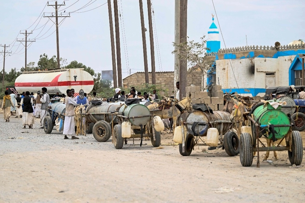Sudaneses buscan abastecerse de agua de una pipa a través de tanques transportados por burros. Foto Afp.