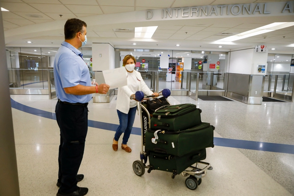 Un trabajador ofrece información sobre vacunas gratuitas de Johnson & Johnson contra Covid-19 en el vestíbulo de llegadas internacionales del Aeropuerto Internacional de Miami, en Miami, Florida el 29 de mayo de 2021. Foto Afp