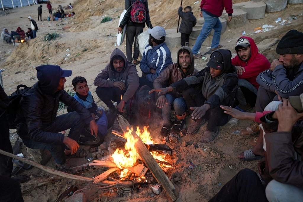 Palestinos se resguardan del frío mientras esperan que se despeje el camino para volver a casa en el noreste de la franja de Gaza.Foto Ap