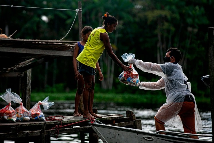 Personal del Ministerio de Educación de Brasil entrega kits de almuerzo escolar gratis para los locales necesitados en Megalco, estado de Pará. Foto Afp