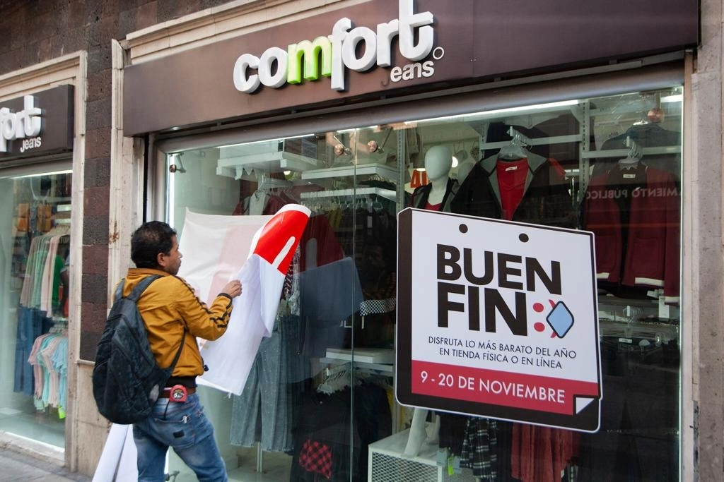 Un trabajador coloca anuncios sobre descuentos del Buen Fin en un comercio de ropa en el Centro Histórico capitalino. Foto Pablo Ramos