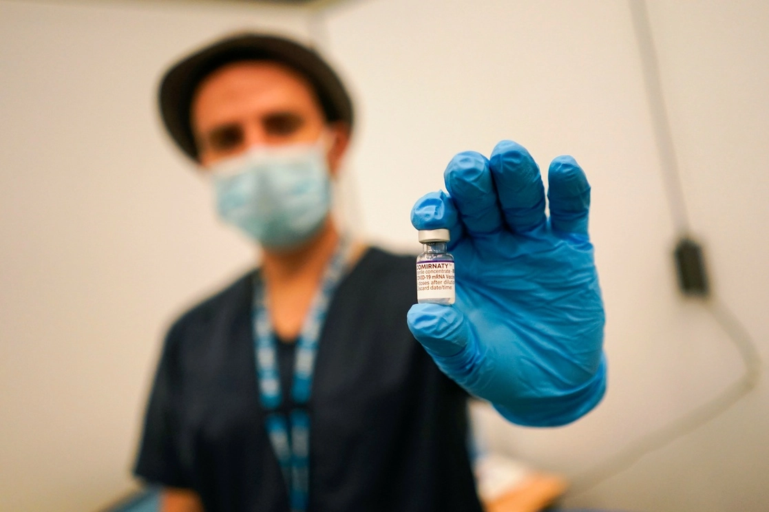 Personal de salud sostiene un frasco de una vacuna Pfizer contra el coronavirus, en el centro de vacunación de la escuela Swaminarayan, en Londres. Foto Ap