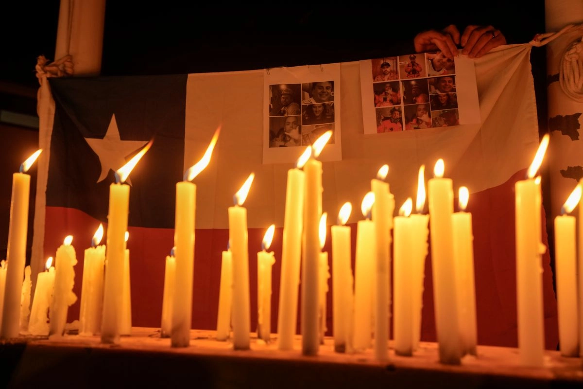 Velas encendidas durante una vigilia con la bandera chilena de fondo y las víctimas de un derrumbe minero, frente a la mina de cobre El Teniente, operada por Codelco, donde un derrumbe mató a un trabajador y atrapó a otros cinco bajo tierra, deteniendo las operaciones en Rancagua, Chile, el sábado 2 de agosto de 2025.