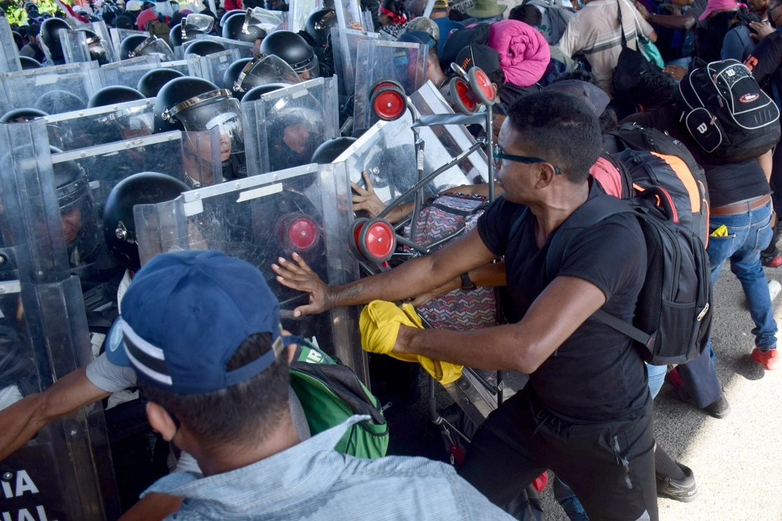 Migrantes chocan con miembros de la Guardia Nacional mientras caminan en una caravana rumbo a la Ciudad de México para solicitar asilo y estatus de refugiado, en Tapachula, Chiapas, el pasado 23 de octubre. Foto Afp