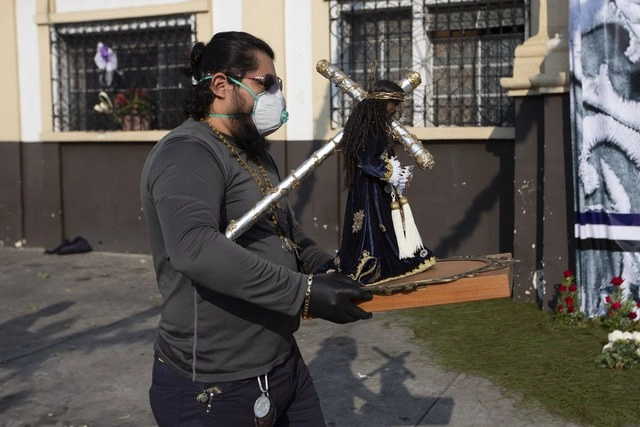 Un hombre carga una estatua miniatura de Cristo Rey frente a una iglesia cerrada de Guatemala. Es la primera vez en 450 años que no se hará la tradicional procesión debido a la pandemia. Foto Ap