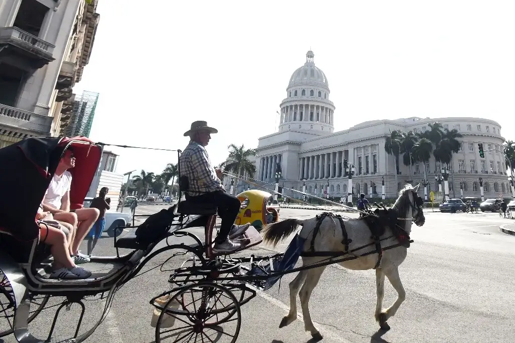 Un carro tirado por caballos pasa frente al Capitolio de La Habana, Cuba. Foto Xinhua.