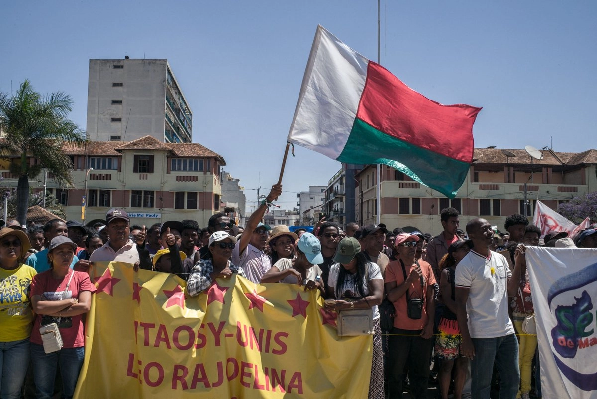 Residentes y manifestantes sostienen pancartas y una bandera malgache durante una manifestación de la  frente al Ayuntamiento en Antananarivo, Madagascar, el 13 de octubre de 2025. 