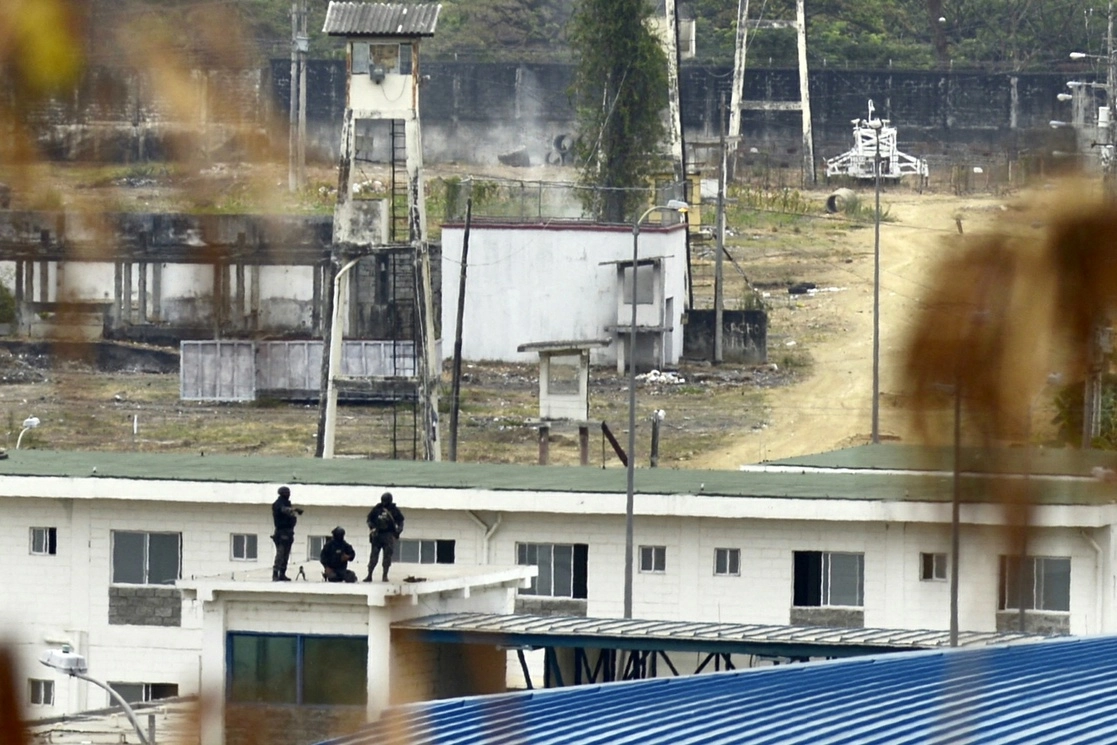 Policías ecuatorianos en el techo de la cárcel regional 8, contigua al penal, en las afueras de Guayaquil. Ecuador desplegó efectivos de la policía nacional y de las fuerzas armadas en todo el sistema penitenciario para garantizar la seguridad en las instalaciones. Foto Afp