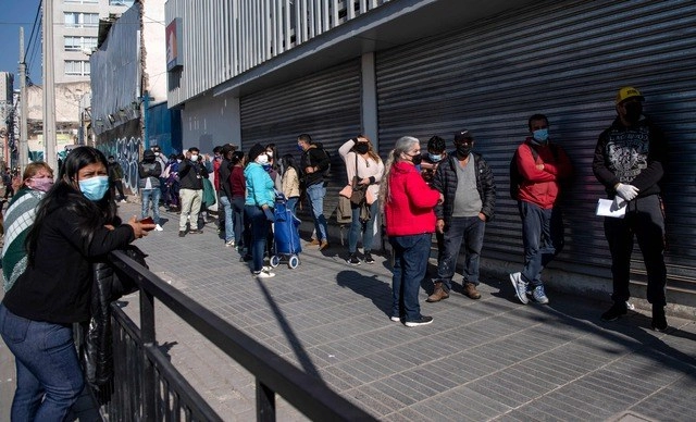 En medio de la pandemia de Covid-19, personas hacen una fila para entrar a una sucursal bancaria en Santiago, Chile. Foto Afp
