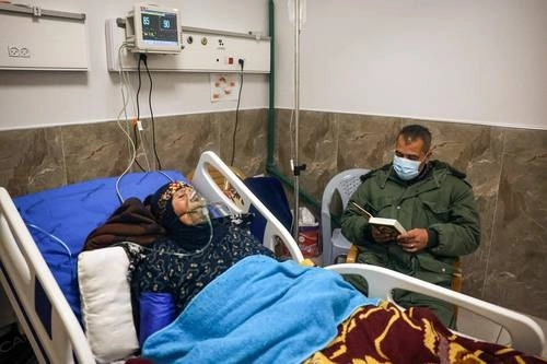 En Cisjordania, un hombre lee el Corán mientras cuida a su paciente en el Hospital Gubernamental Dura. Foto Afp